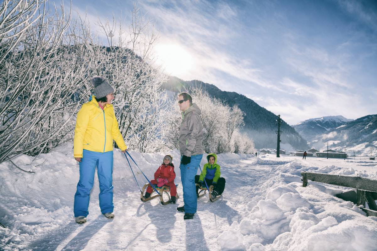 Familie im Schnee mit Kindern auf Schlitten