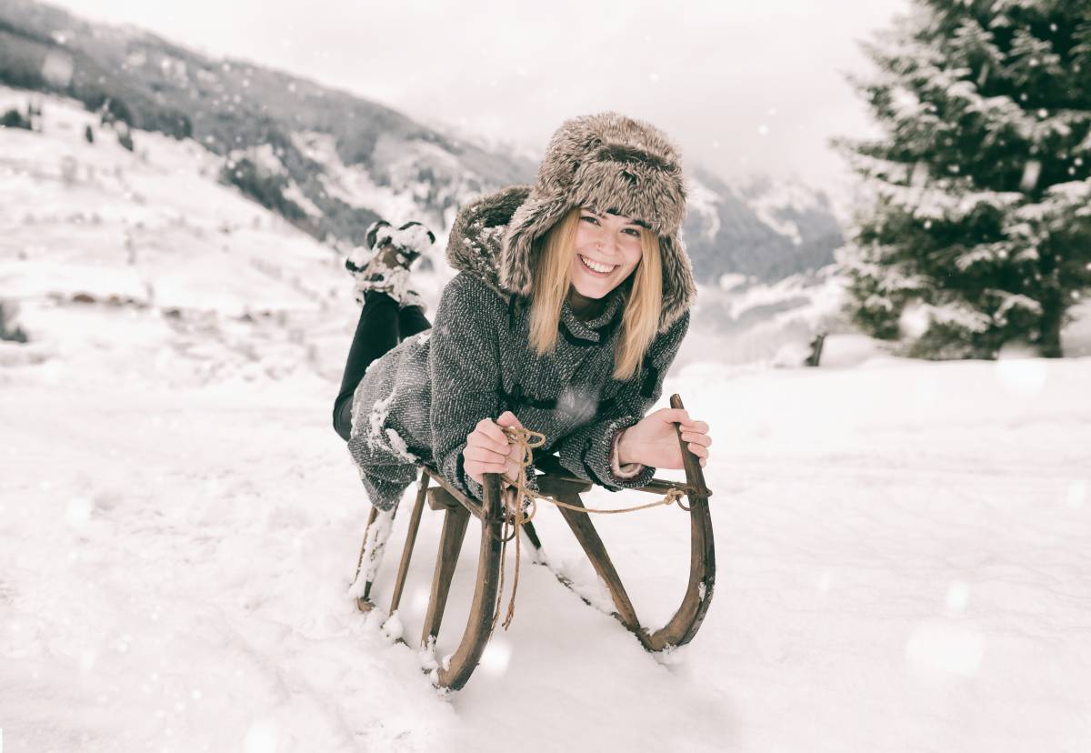 Frau beim Schlitten fahren im Schnee